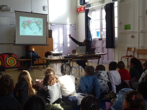 L'artiste Malala Andrialavidrazana dans la classe élémentarires Saint-Lambert présente aux scolaires les images qui constituent son œuvre.
