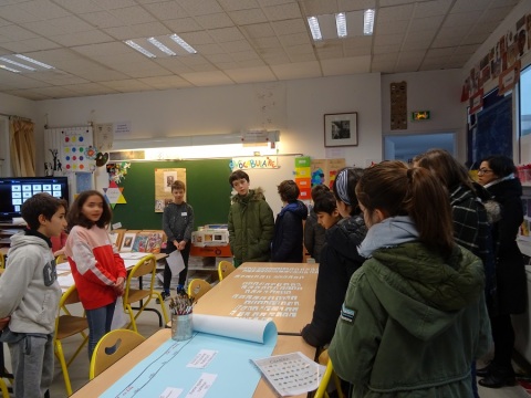 Dans une salle de l'école élémentaire Houdon (18e), les élèves présentent la photographie en noir et blanc du duo d'artistes Florisa, accrochée à droite du tableau, aux élèves du collège Yvonne-le-Tac (18e).