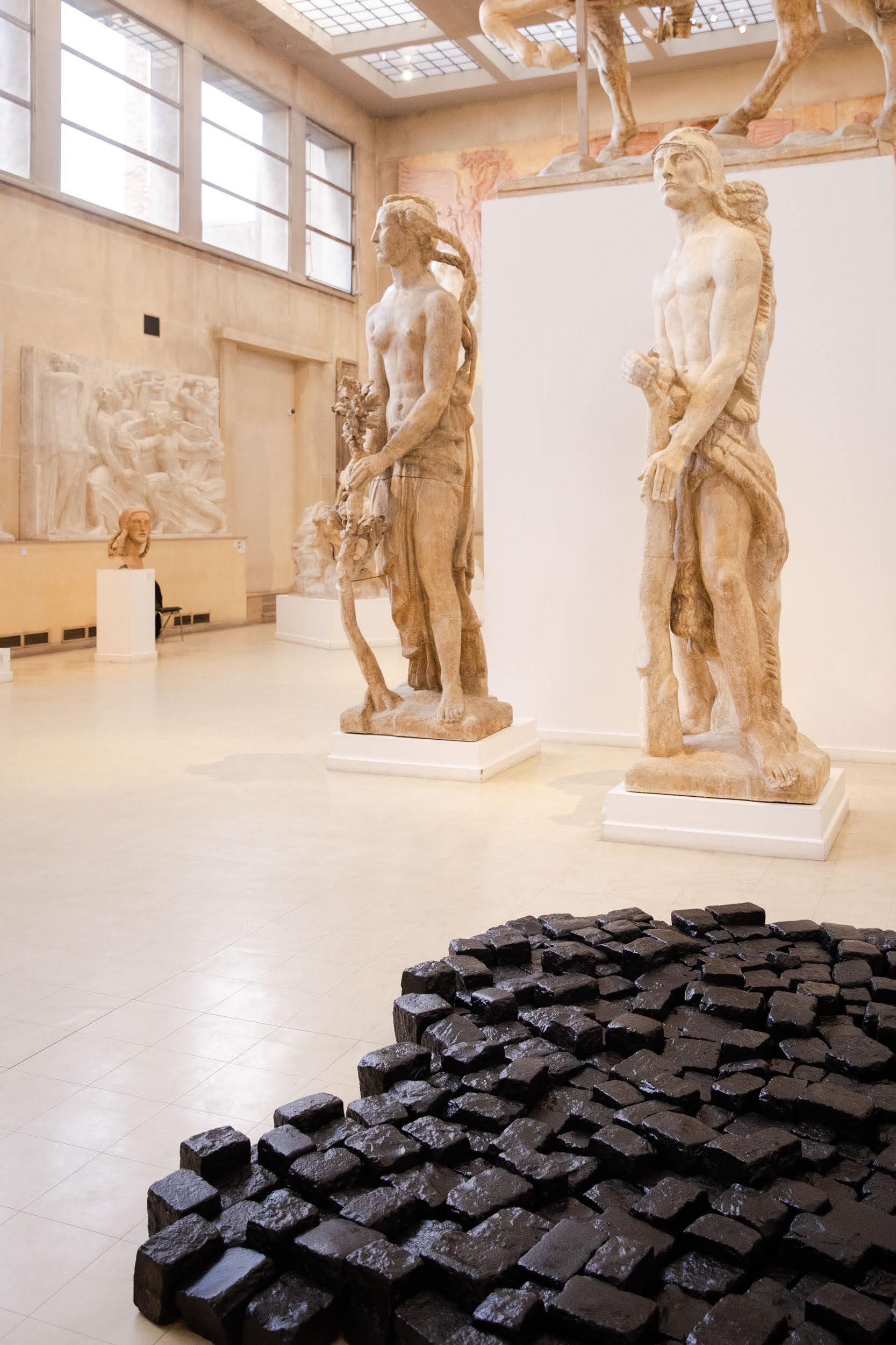 sculpture composée de pavés parisiens foncés sur un sol clair d'un musée avec des sculptures monumentale de Bourdelle