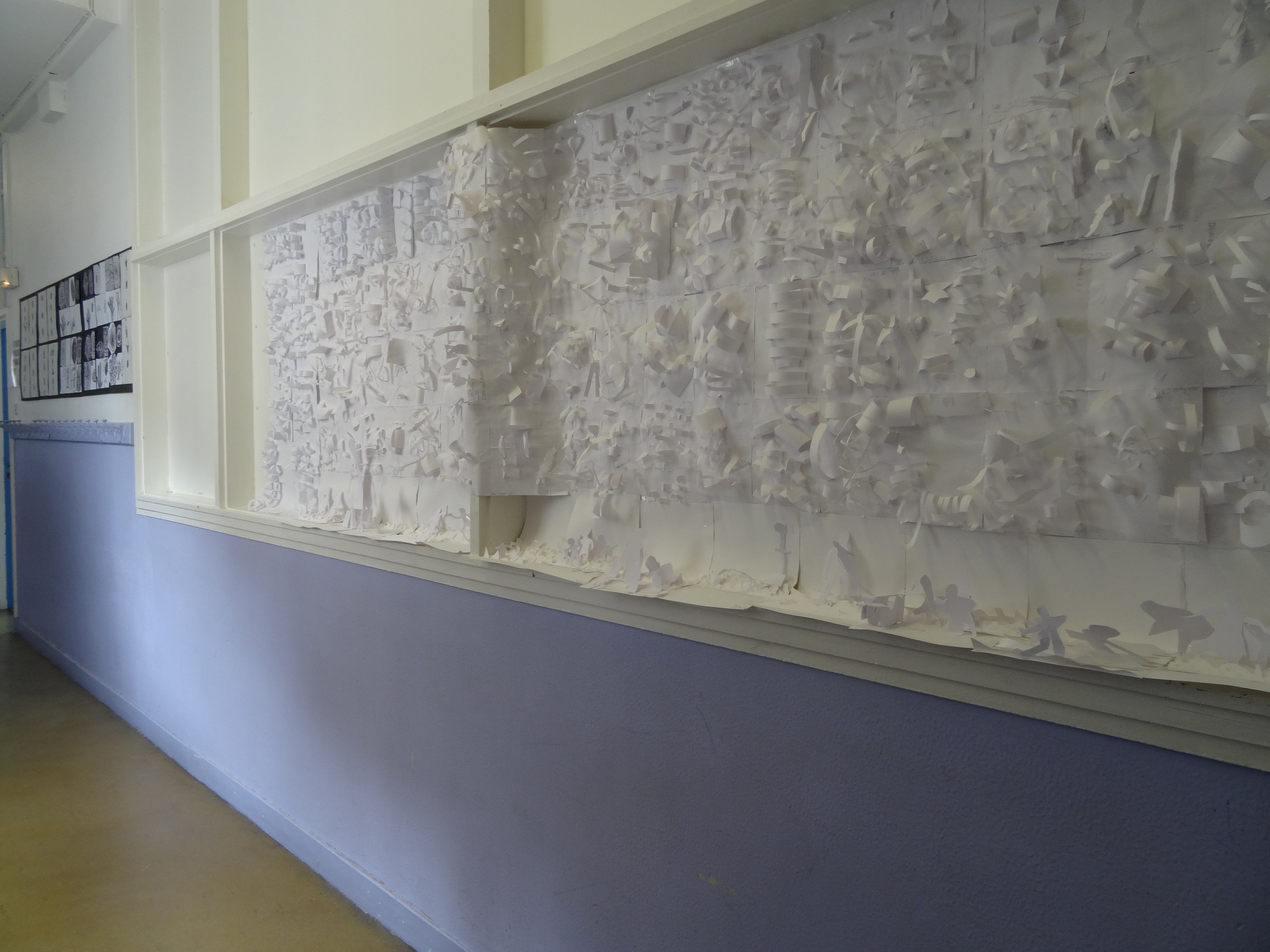 Dans un couloir de l'école élémentaire Keller (11e) est affichée une fresque blanche représentant toutes formes de paysages en papier, inspirée de la vidéo de l'artiste Grégory Chatonsky.