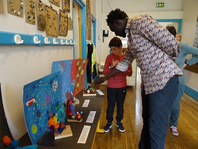 L'artiste Omar Ba regarde des travaux d'élèves