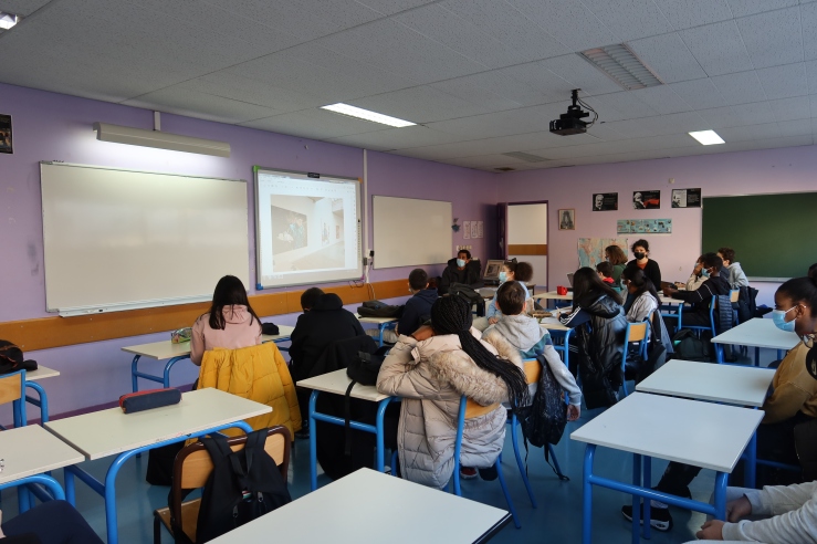 es élèves sont en classe et l'artiste présente son travail avec une projection