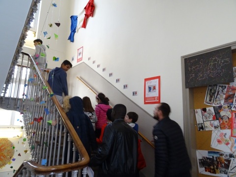 Des lycéen.ne.s montent un escalier au lycée Lucas de Nehou (5e) pour découvrir les assiettes créées par des élèves de la classe d'UPE2A qui y sont exposées.