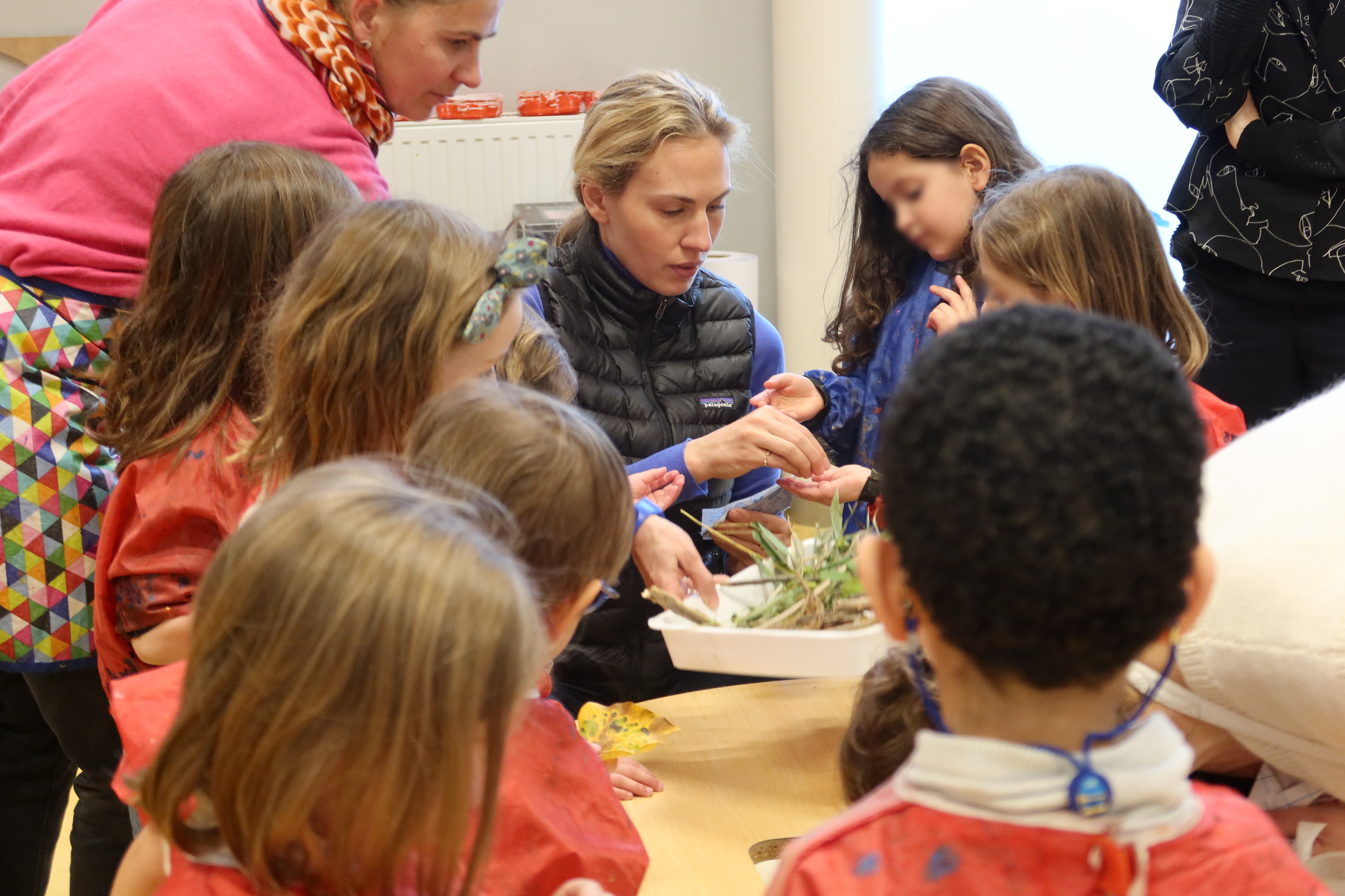 Mia Marfurt distribue des feuilles et des brindilles aux enfants pour réaliser des pochoirs