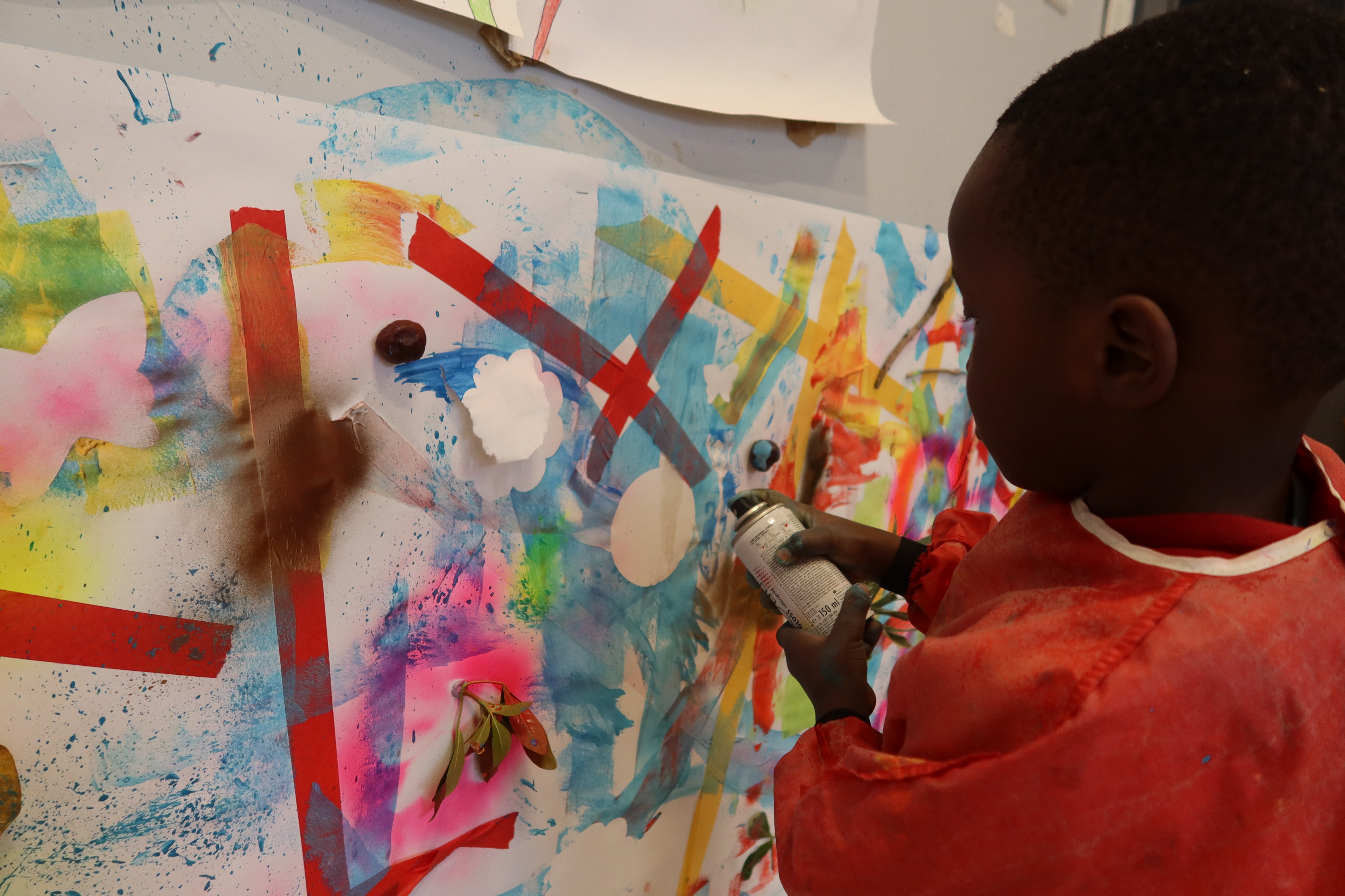 Un enfant peint à la bombe aérosol par-dessus les pochoirs qu’il vient de coller