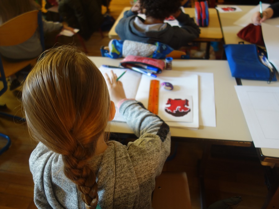 Photographie d'une scolaire à son bureau réalisant une bande dessinée à partir de l'œuvre [Robe Rouge], de Valérie Favre.