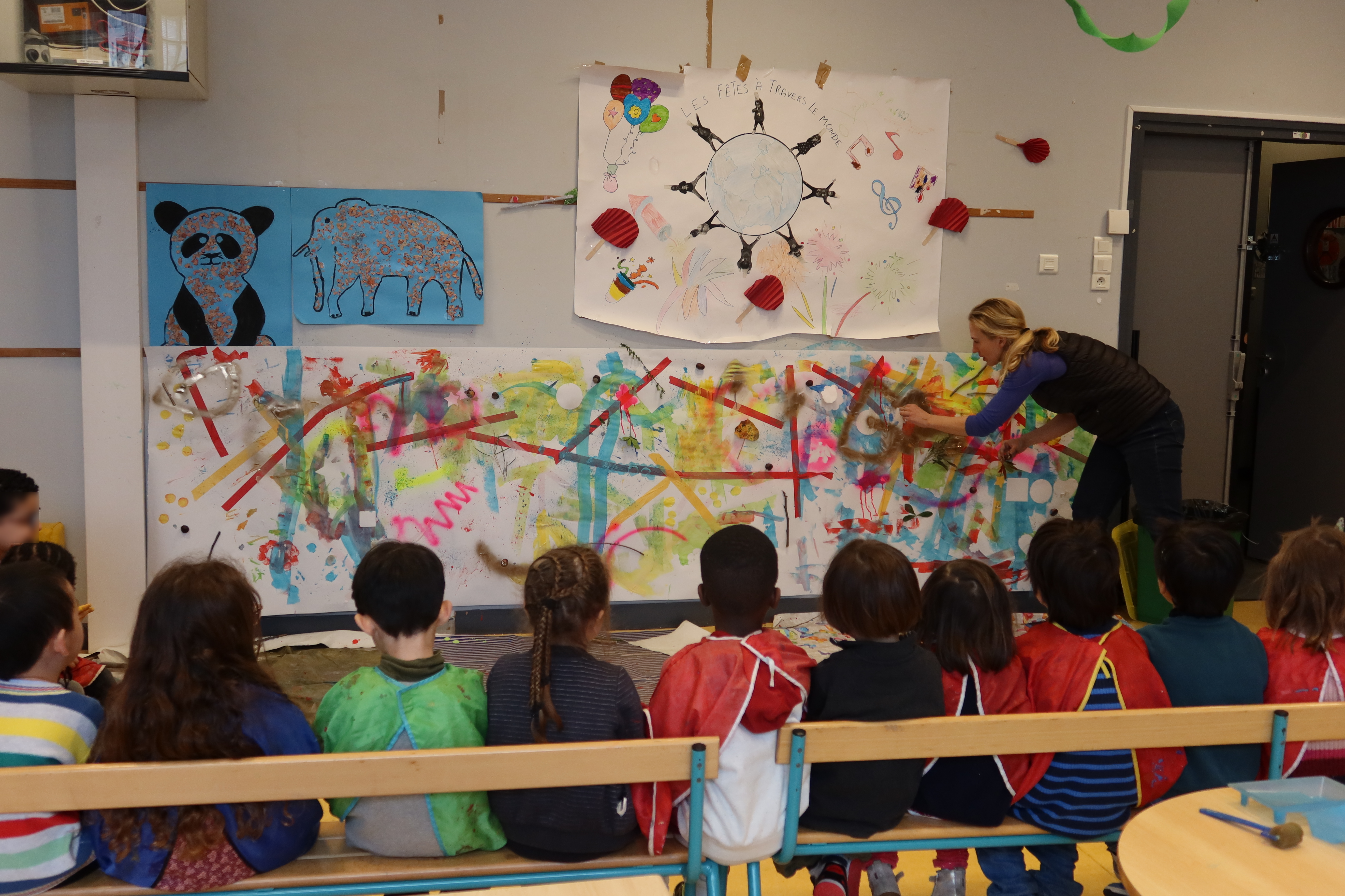 Mia Marfurt décolle une forme sur la fresque des enfants pour leur montrer comment fonctionnent les pochoirs