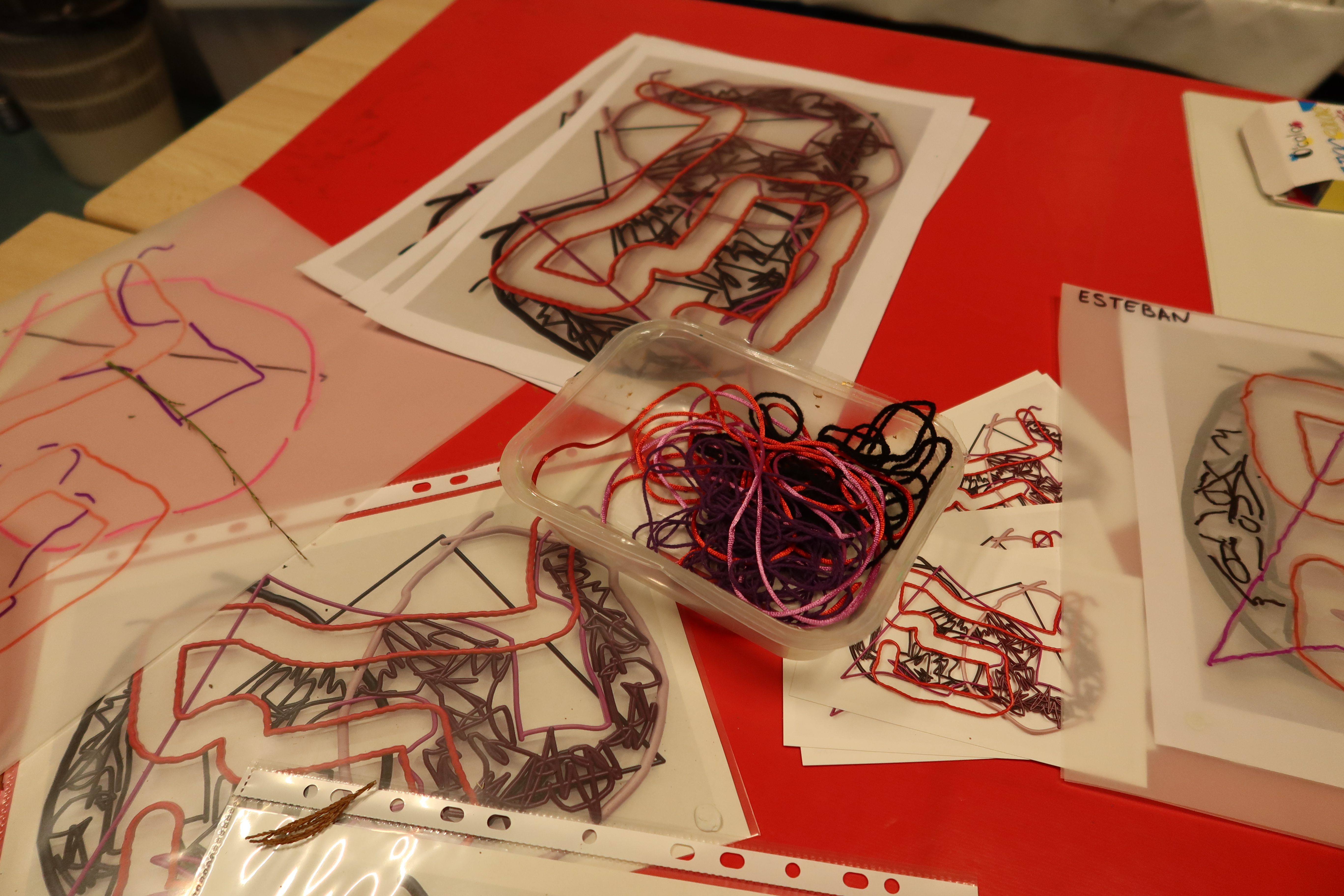 Des collages de fils de laine dans des pochettes transparentes reposent sur une table. A côté d'eux sont posées des photocopies de l'oeuvre, Duroc, de Mia Marfurt.